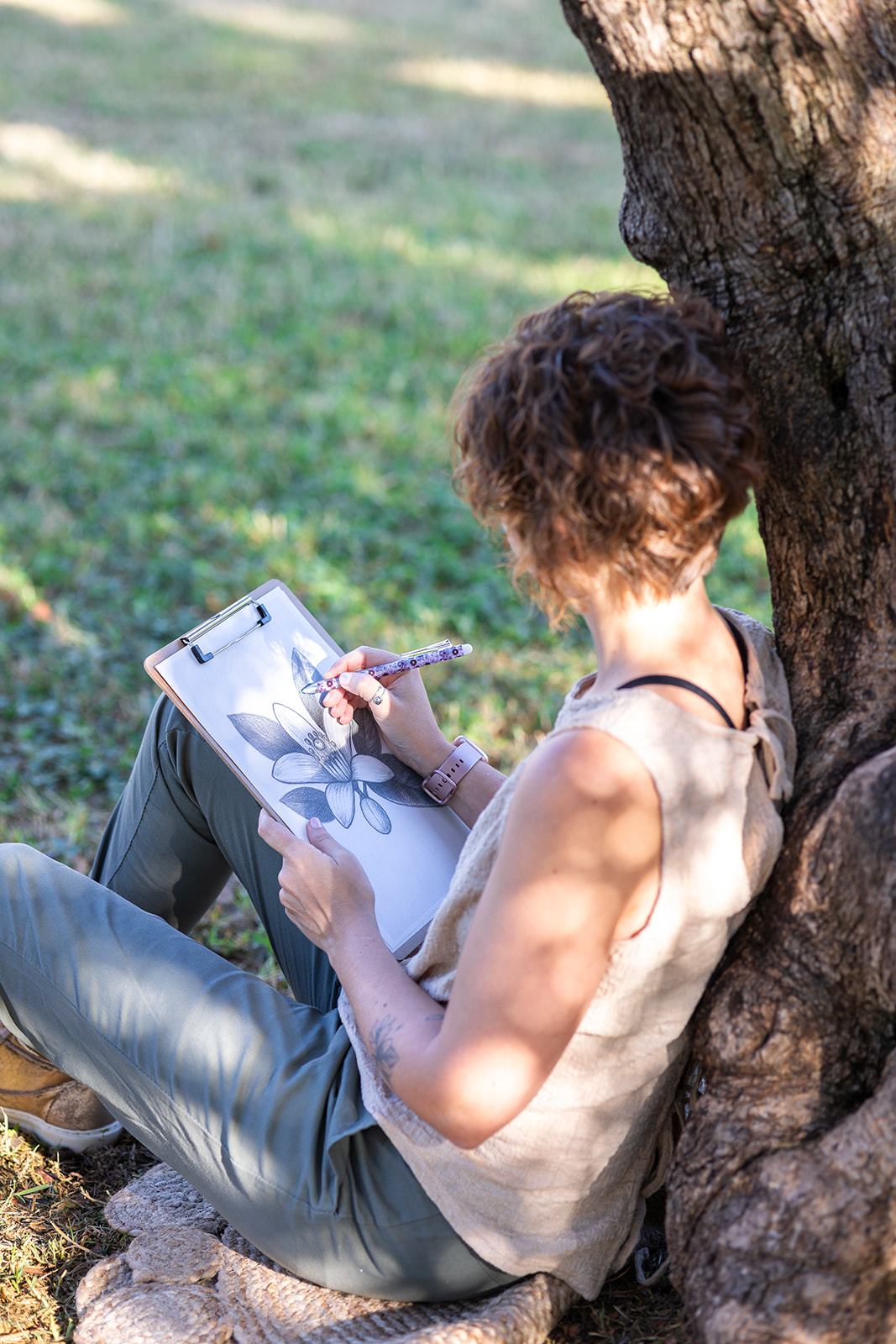Berta Torres sentada bajo un árbol, en un momento de calma y reflexión, simbolizando autenticidad y conexión interior.