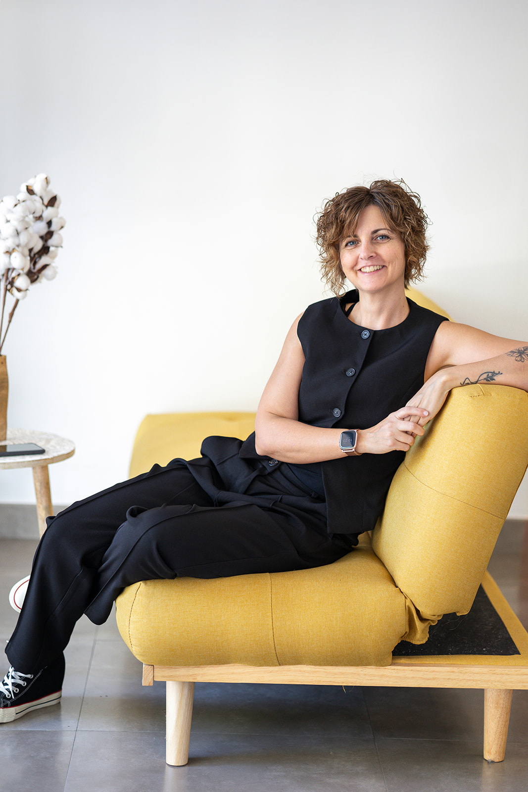 Berta Torres sentada en un sofá amarillo, con actitud relajada y segura, reflejando cercanía y equilibrio en su marca personal.